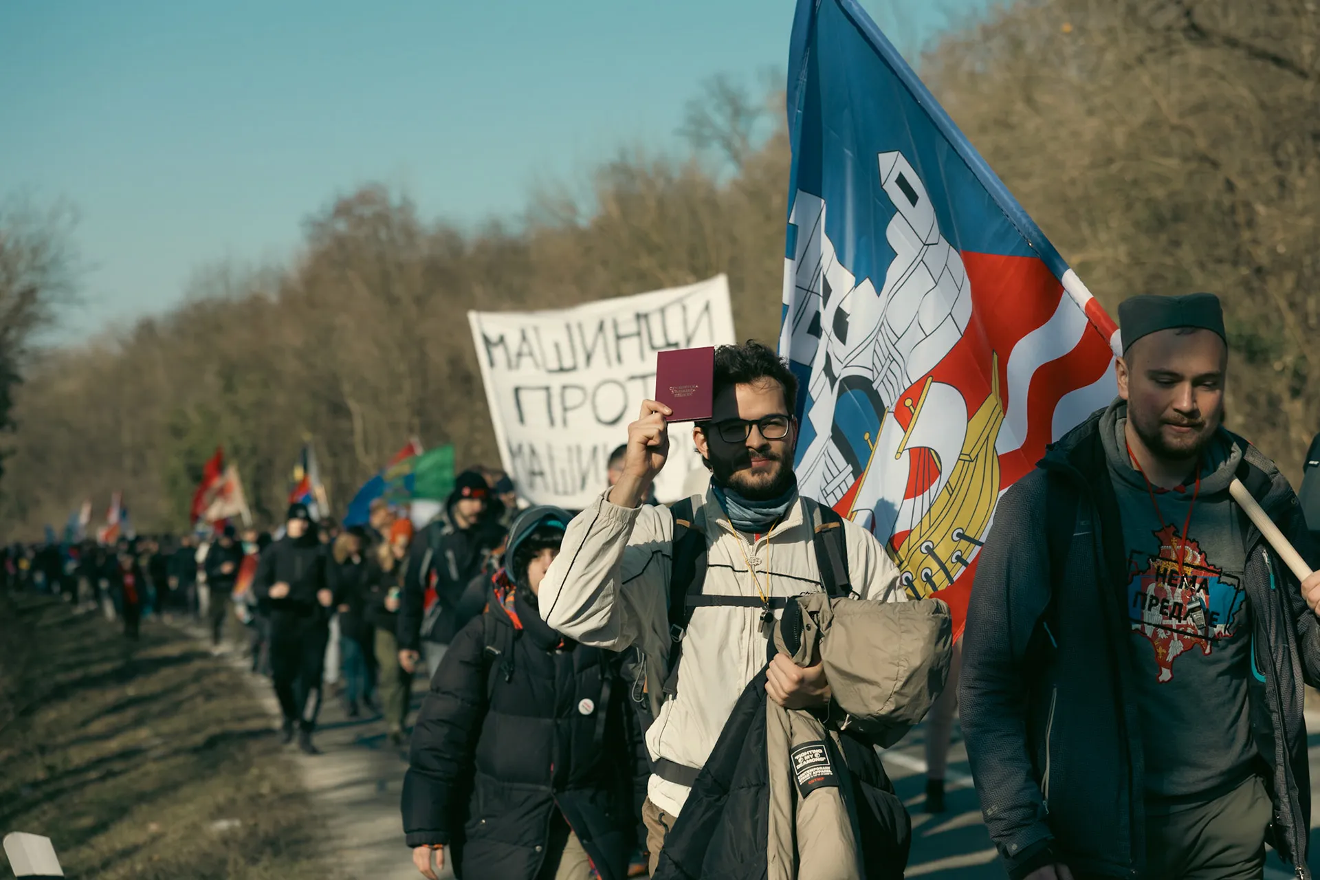 Dugačka kolona studenata, u centru kadra se nalaze student sa indeksom i njegov kolega sa zastavom grada Beograda.