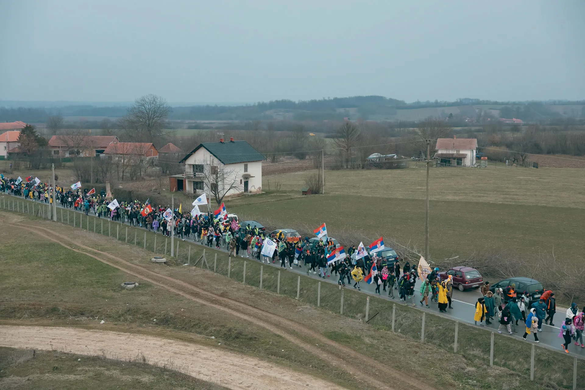 Šarena kolona studenata prolazi selom. Okruženi travom i seoskim putevima, radosno vijore zastavama.